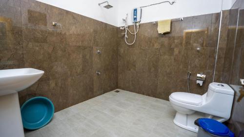 Un baño con inodoro, lavabo y ducha. en Woodsy Villa, en Sigiriya