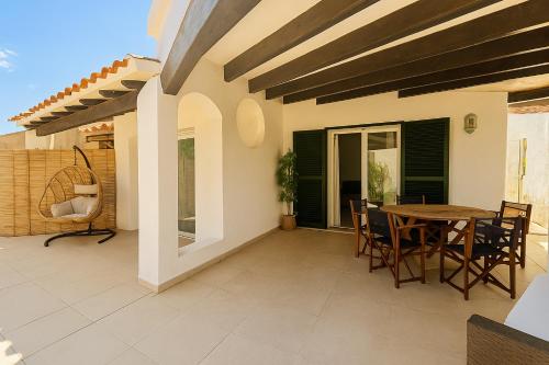 a patio with a wooden table and chairs at VILLA MAR in Cala'n Bosch