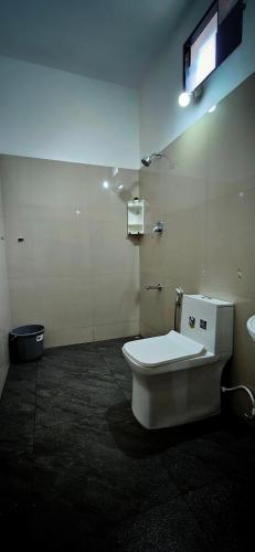 a bathroom with a toilet and a television on the wall at Goodkarma Inn in Cochin