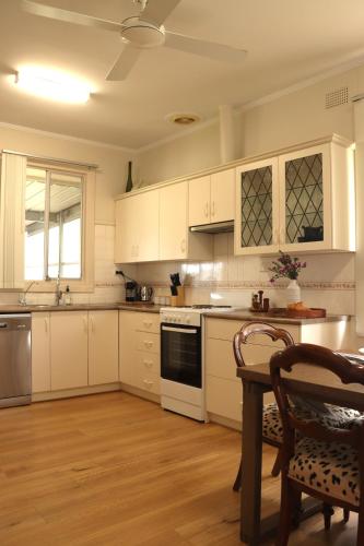 a kitchen with white cabinets and a table and chairs at Vale & Vine in McLaren Vale