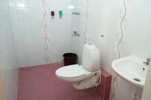 Un baño con un inodoro blanco y un lavabo. en Deepam Haven Inn, en Gūduvāncheri