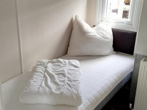 ein weißes Bett mit zwei Kissen darüber in der Unterkunft Luxus Chalet im schönen Recratiepark De Veerstal in Rheden