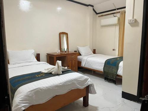 Una habitación de hotel con dos camas y un espejo. en Janh Ya Phone Guesthouse, en Pakbeng