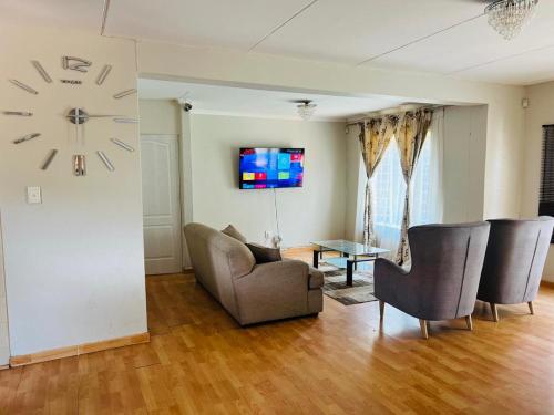 ein Wohnzimmer mit Stühlen und einer Uhr an der Wand in der Unterkunft Pelistay in Sundowner in Boskruin