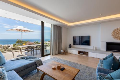 a living room with a couch and a tv and a table at Plett Quarter Apartments in Plettenberg Bay
