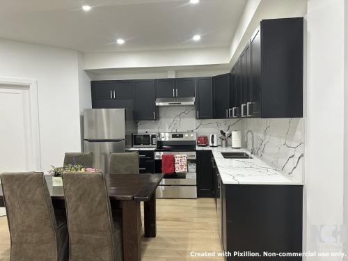 une cuisine avec des armoires noires et une table avec des chaises dans l'établissement Modern 2-Bedroom Apartment in Luxury Home with Gym, à Colline De Richmond