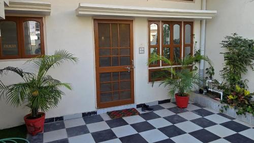 a house with two potted plants in front of a door at Aditi Premium Homestay GF in Jabalpur