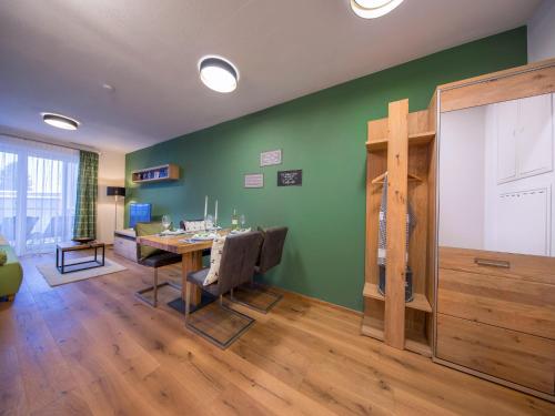 a dining room with a table and a green wall at Apartment in the heart of Neukirchen in Neukirchen am Großvenediger