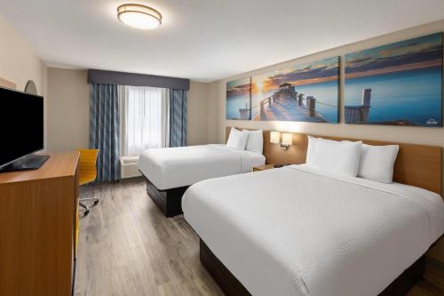 a hotel room with two beds and a flat screen tv at Days Inn by Wyndham Lincoln in Lincoln