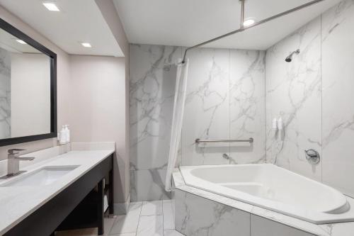a white bathroom with a tub and a sink at Days Inn by Wyndham Lincoln in Lincoln