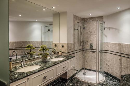 a bathroom with two sinks and a shower at Main Plaza Suite Tower in Frankfurt/Main