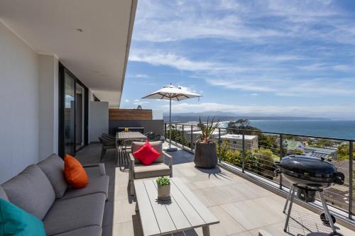 a balcony with a couch and a grill and the ocean at Plett Quarter Apartments in Plettenberg Bay