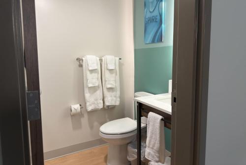 a bathroom with a toilet and a sink and towels at Wingate by Wyndham Geneva at SPIRE Academy in Geneva