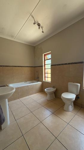a bathroom with a tub and a toilet and a sink at The Palm Tree in Saldanha