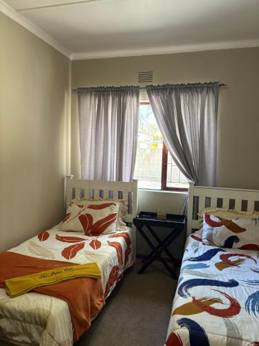 a bedroom with two beds and a window at The Palm Tree in Saldanha