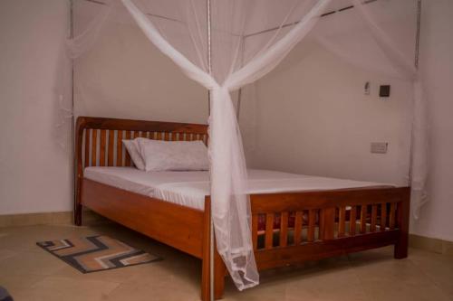 a wooden bed with a canopy in a room at Off Airport Kilimanjaro lodge in Boma la Ngombe