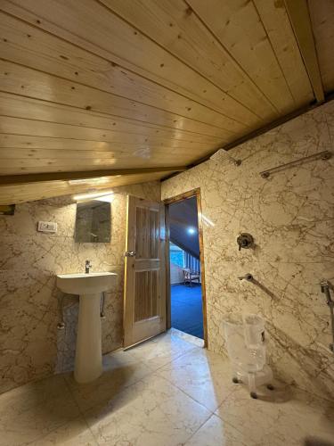 a bathroom with a sink and a wooden ceiling at The Woodpecker Inn Jibhi in Jibhi