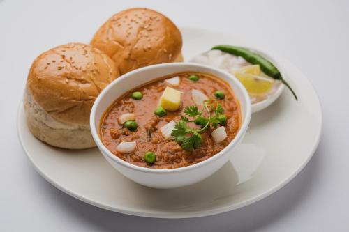 un tazón de sopa en un plato con pan en Super Hotel O Pathanamthitta Near Mahatma Gandhi Statue, en Pathanāmthitta