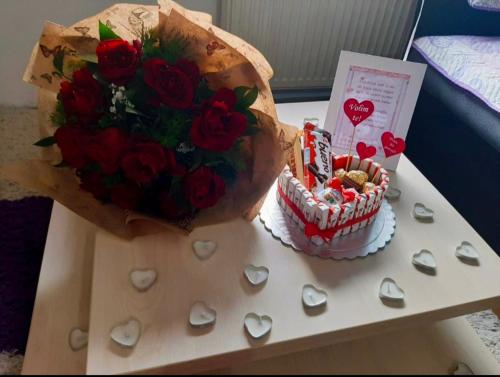 a table with a cake and a bouquet of roses at Jednosoban stan centar Ela in Pirot