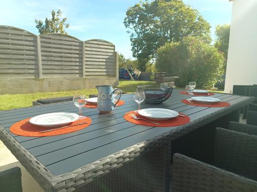 een houten tafel met borden en glazen erop bij L'Estran qu'Île - Proche plages in LʼÎle-dʼOlonne