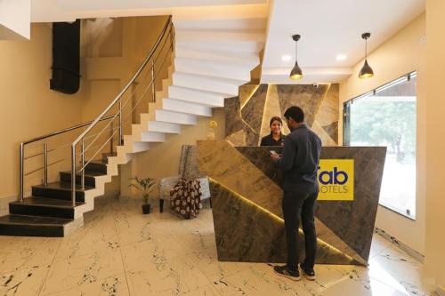 een man die met een vrouw aan een balie in een lobby staat bij FabHotel Blueark in Lucknow
