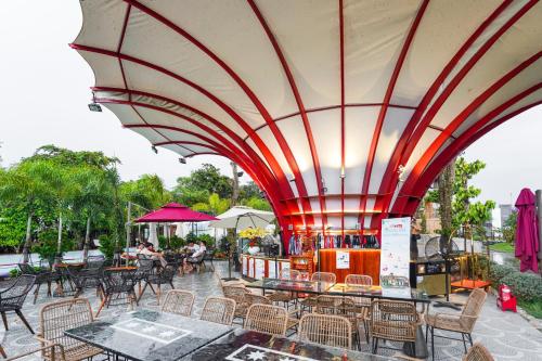 an outdoor patio with tables and chairs and a large umbrella at NV Sport Camping & Hotel - Ho Tram in Xuyên Mộc