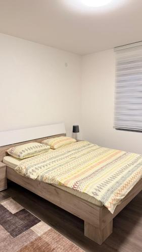 a bed in a bedroom with a white wall at Apartman Paradiso in Pirot
