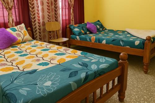 a room with two beds and a chair at Pushpa Nilaya in Madikeri