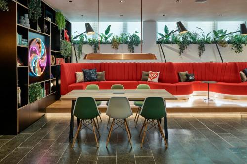 a living room with a red couch and green chairs at citizenM London Victoria Station in London
