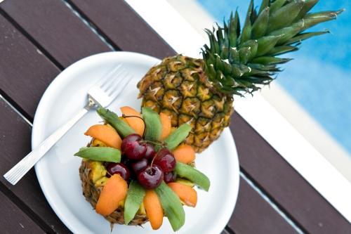 a plate of fruit on a table with a pineapple at Stratos Hotel in Afitos