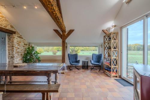 ein Esszimmer mit Tisch und Stühlen und großen Fenstern in der Unterkunft La meulière de Guerlande - Disney 20min in Lumigny