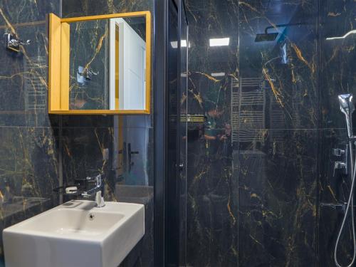 a bathroom with a sink and a mirror and a shower at Deluna Ümitköy Suite in Çayyolu