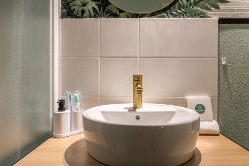 a white bath tub with a gold faucet in a bathroom at L'éléhouse Studio Terrasse à RIOM in Riom