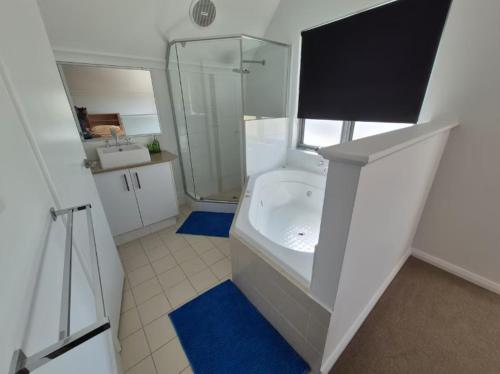un bagno bianco con doccia e vasca di Serenity by the Sea a Mandurah