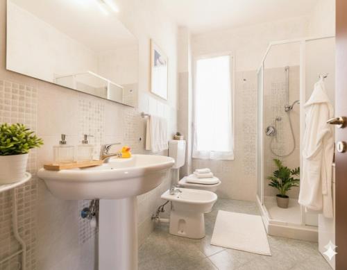 a white bathroom with a sink and a toilet at Casa Conca Azzurra in Costarainera
