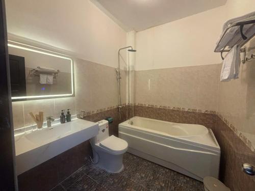 a bathroom with a tub and a toilet and a sink at Hoang Cung Hotel in Ấp Phú Thọ