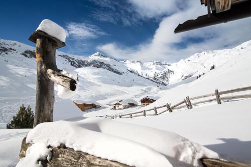 a fence covered in snow with mountains in the background at Hotel Eden in Tux