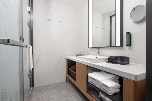a bathroom with a sink and a mirror at 海口国贸希尔顿欢朋酒店 in Haikou