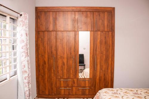 einen großen Holzschrank in einem Schlafzimmer mit Spiegel in der Unterkunft 2Bedroom Apartment at Pokuase in Ayaso