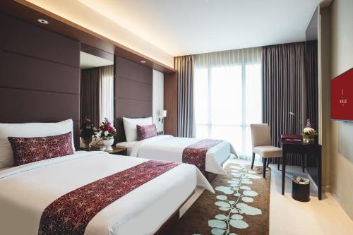 een hotelkamer met twee bedden en een raam bij The Margo Hotel in Depok