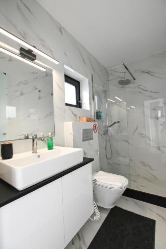 a white bathroom with a sink and a toilet at Gestema Luxury Residences in Kalymnos