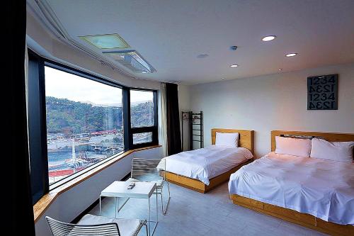 een slaapkamer met twee bedden en een groot raam bij Nine Boutique Hotel in Seogwipo