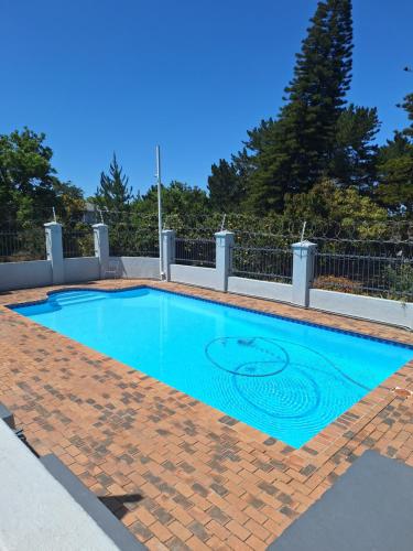 a blue swimming pool with a brick floor and fence at Serengeti Heide Self Catering Flats in Cape Town