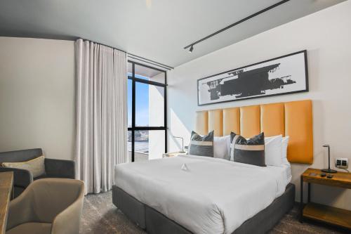 a hotel room with a large bed and a chair at The Capital Mbombela in Nelspruit