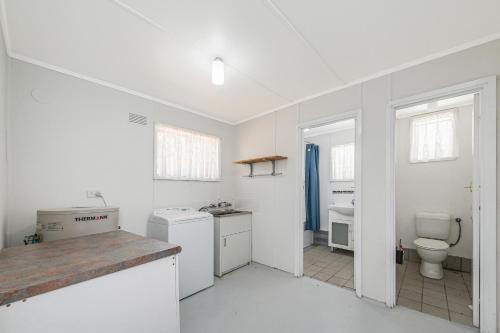 a white kitchen with a sink and a toilet at Ocean Moore - Uninterrupted Ocean Views in Guilderton