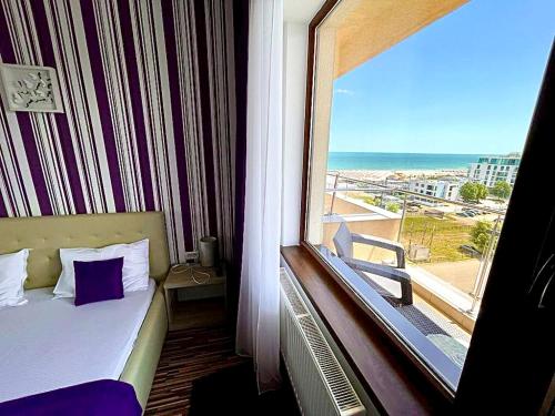 a room with a bed and a window with a view of the ocean at Marcony Seaview Apartments in Mamaia