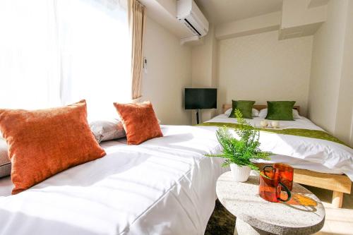 2 camas en una habitación con sábanas blancas y almohadas de color naranja en Mr Kintaro Hotel Kinshicho, en Tokio