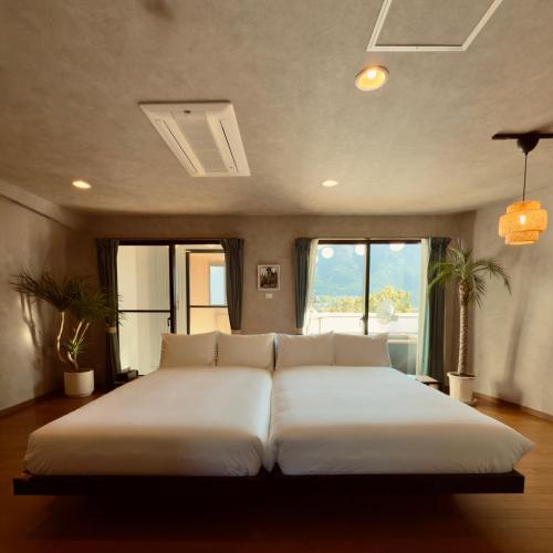 a large white bed in a room with windows at Shiki Art Hotel Yufu in Yufu