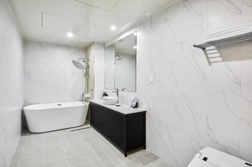 a white bathroom with a tub and a sink at Hoteld Benikea in Osan