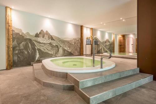 a bathroom with a tub with a painting of mountains at Alpenappart in Cadipietra